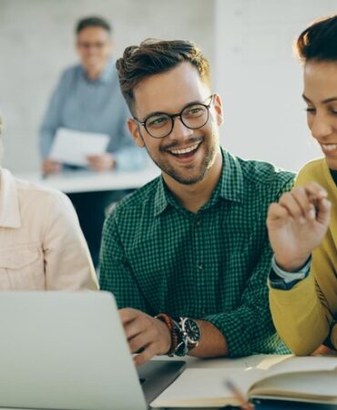 estudiante-feliz-divirtiendose-mientras-usa-computadora-portatil-sus-amigos-aula_637285-8830